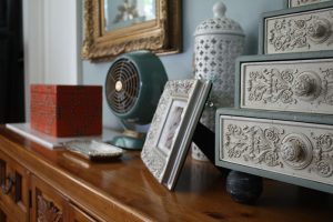 Wooden desk with picture frame, fan, and a decorated box