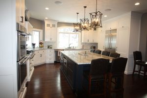 Kitchen with island countertop, chairs, sink, light fixtures, stove, oven and windows