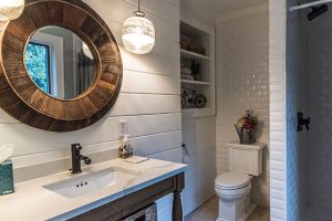 Bathroom with toilet, shower and Sink with mirror and hanging light fixtures